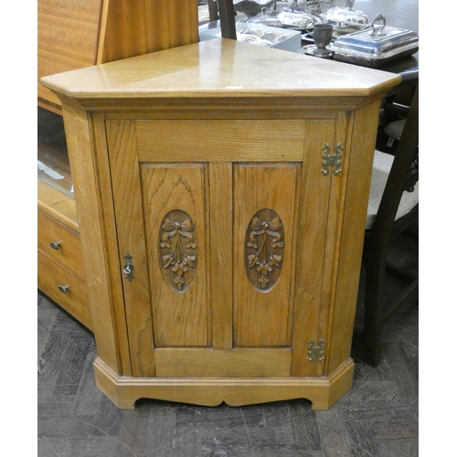 55 - A modern light oak low corner cupboard with carved panel doors.