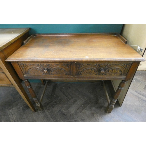 95 - A reproduction carved oak hall table on turned legs fitted with two drawers. 3' wide