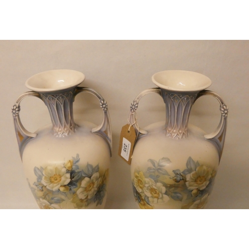 235 - A pair of continental porcelain twin handled vases, decorated with roses with gilt highlights. 40 cm... 