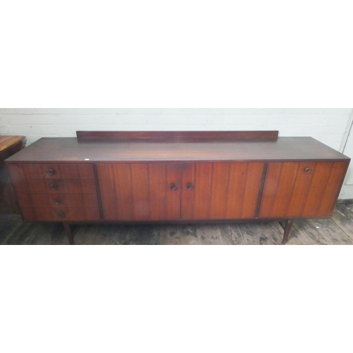 109 - A long low dark teak 1960's/1970's sideboard, fitted four drawers, centre cupboards and drop-down wi... 