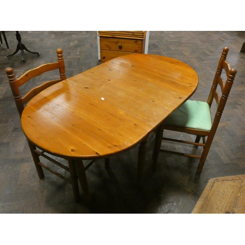 312 - A pine oval drop leaf dining table and a pair of ladder back chairs