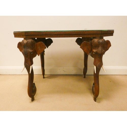 348 - An Indian elephant carved hardwood coffee table standing on elephant trunk supports with glass top, ... 