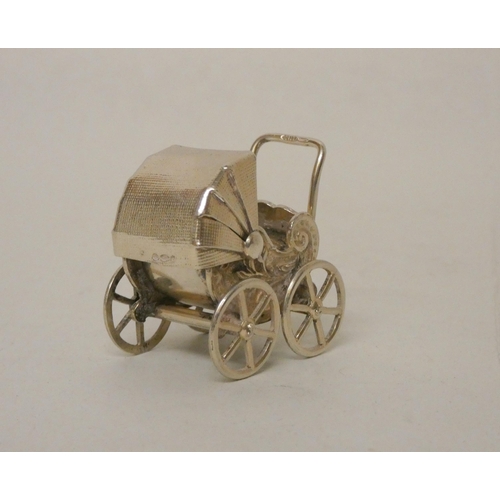 528 - A miniature silver novelty pram with moving wheels. Import hallmarks. Height 3.3cm tall