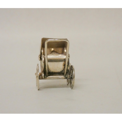 528 - A miniature silver novelty pram with moving wheels. Import hallmarks. Height 3.3cm tall