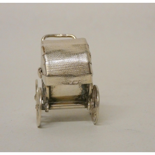 528 - A miniature silver novelty pram with moving wheels. Import hallmarks. Height 3.3cm tall