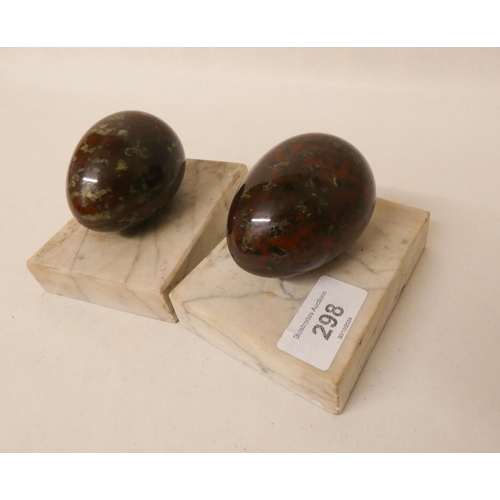 298 - A pair of serpentine and marble eggs on marble bases