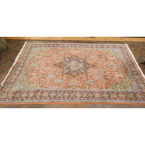 392 - A silk pile Persian carpet decorated with a central medallion on a salmon pink ground, measuring 69