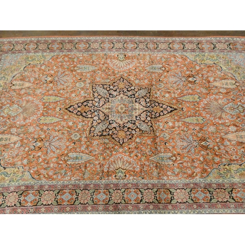 392 - A silk pile Persian carpet decorated with a central medallion on a salmon pink ground, measuring 69