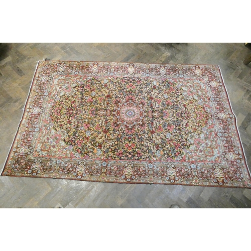 393 - A Persian carpet decorated with floral designs and central medallion in pinks and reds measuring 95