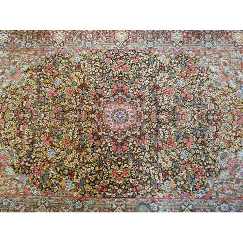 393 - A Persian carpet decorated with floral designs and central medallion in pinks and reds measuring 95