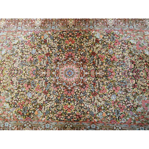 394 - A Persian carpet decorated with floral designs and central medallion in pinks and reds measuring 95