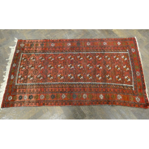 396 - A modern Persian Balouch style rug, decorated with medallions on a red ground measuring 79