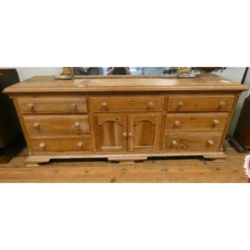 365 - A large stripped and waxed pine dresser base fitted seven drawers with cupboards each side