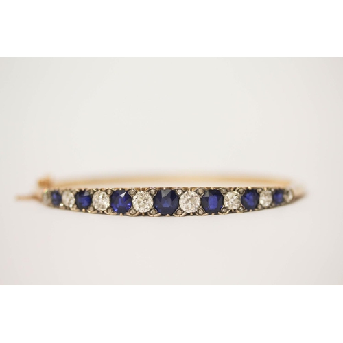 707 - An early 20th century old cut sapphire and diamond hinged bangle, set with seven circular sapphires ... 