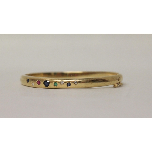 637 - A multi gem set 18ct yellow gold hinged bangle. Pave set with diamonds, sapphires, emerald and ruby,... 