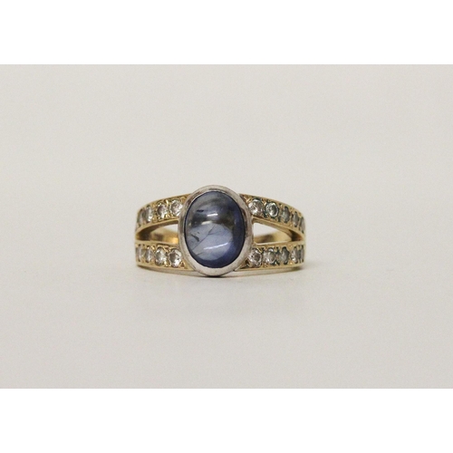 639 - A star sapphire and diamond ring, the oval sapphire bifurcated pave diamond set shoulders. On 18ct y... 