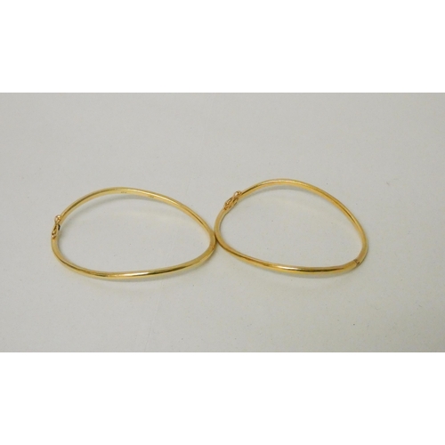 657 - A pair of 18ct yellow gold shaped bangles, of bespoke hinged design, stamped 18ct. Gross weight 31.2... 