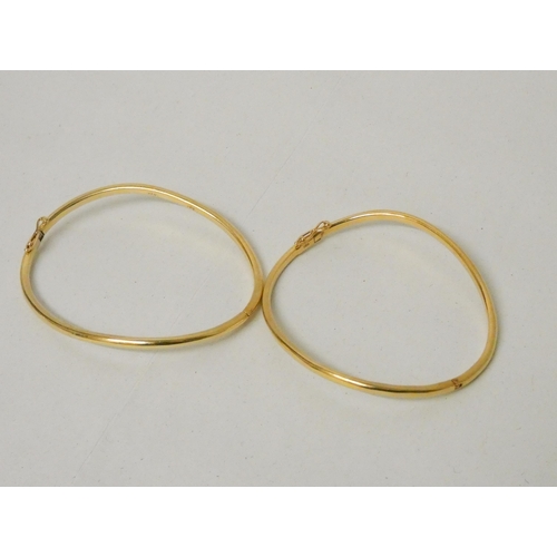 657 - A pair of 18ct yellow gold shaped bangles, of bespoke hinged design, stamped 18ct. Gross weight 31.2... 