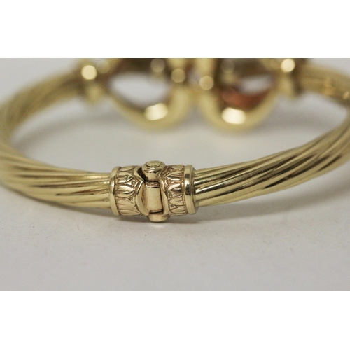 705 - Good quality modern 18ct tri-colour gold hinged bangle, with central knot designing three differing ... 