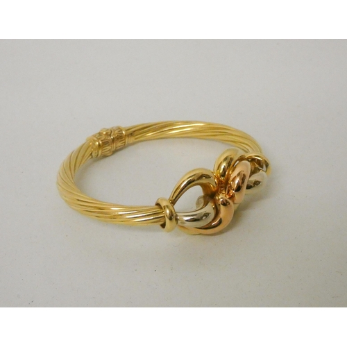 705 - Good quality modern 18ct tri-colour gold hinged bangle, with central knot designing three differing ... 