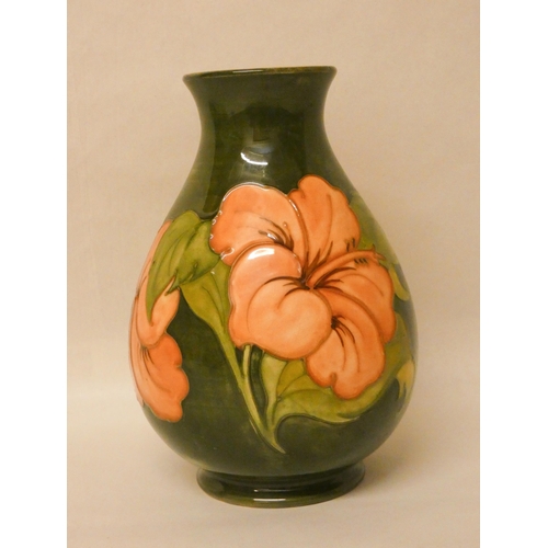 245 - A green Moorcroft pottery vase decorated with hibiscus flowers. 21cm high approx.