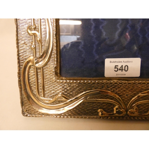 540 - An Art Nouveau silver embossed framed easel photo frame, the embossed floral stylised decorated silv... 