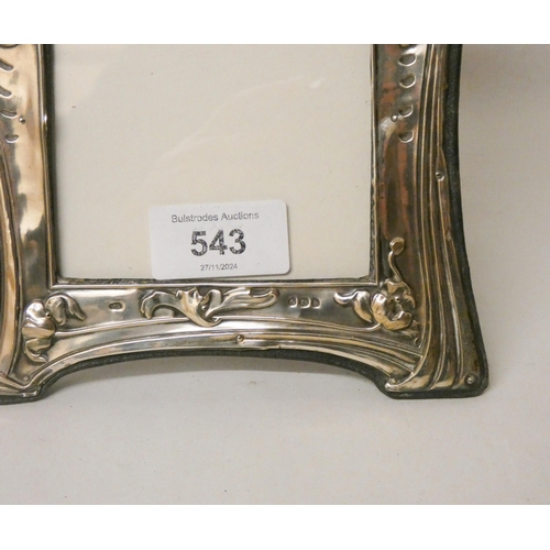 543 - An Art Nouveau silver embossed framed easel photo frame, embossed with a cherub holding flowers appl... 