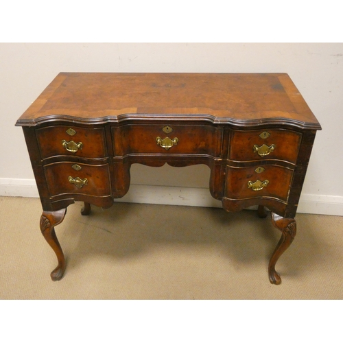 430 - A figured walnut knee-hole desk with crossbanded top and a shaped front, fitted five drawers with br... 