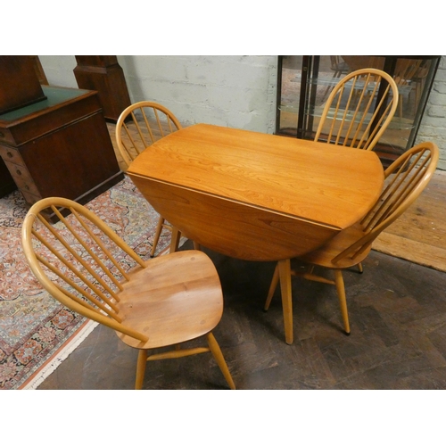 444 - An Ercol circular blonde elm dining table and four Windsor style spindle backed chairs with panel se... 