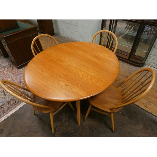 444 - An Ercol circular blonde elm dining table and four Windsor style spindle backed chairs with panel se... 