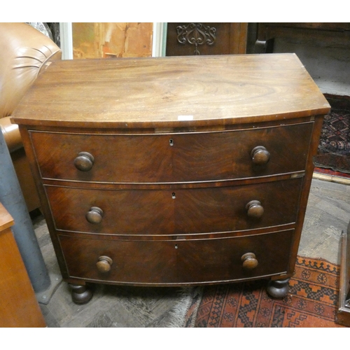 417 - A Victorian mahogany bowfront chest of three long drawers with bun handles standing on turned feet, ... 