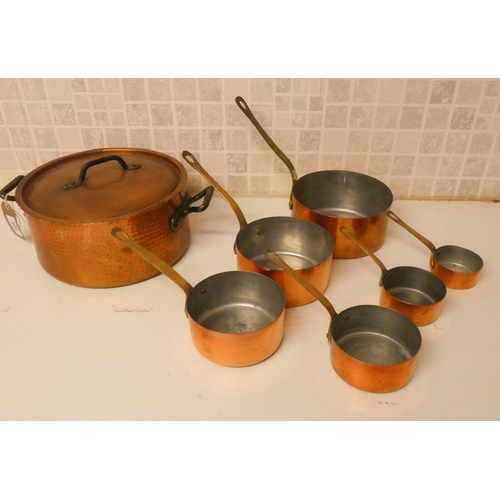 859 - A set of six graduating copper saucepans with brass handles and a planished copper casserole dish wi... 