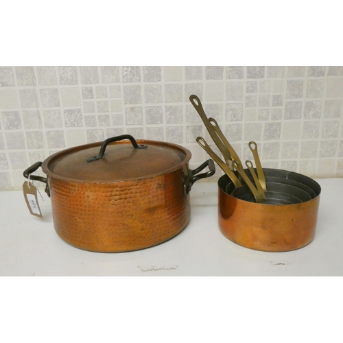 859 - A set of six graduating copper saucepans with brass handles and a planished copper casserole dish wi... 