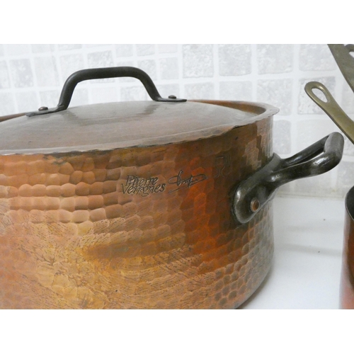 859 - A set of six graduating copper saucepans with brass handles and a planished copper casserole dish wi... 