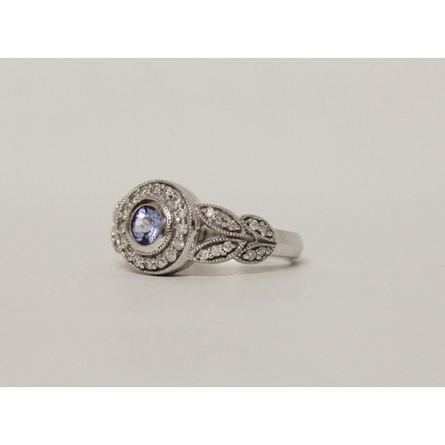 596 - A modern tanzanite and diamond dress ring, the circular tanzanite in 14K white gold collet setting w... 