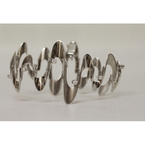 624 - A Modernist 18ct white gold and diamond set wavy design bracelet, with polished and matt sections se... 