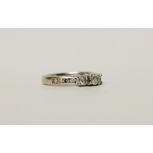 625 - A diamond three stone ring, with channel set diamond shoulders. 14k white gold band. Ring size N, 3.... 