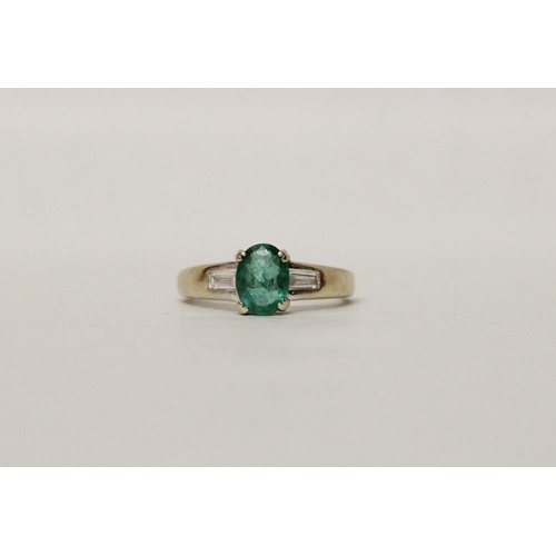 626 - An emerald and diamond ring, the oval claw set emerald flanked by baguette cut diamond shoulders, on... 