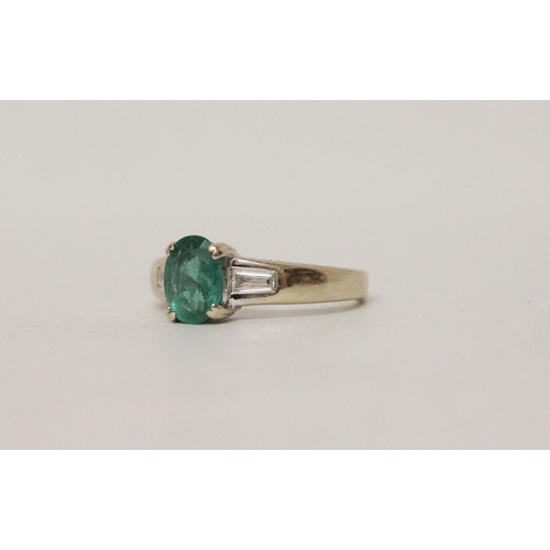 626 - An emerald and diamond ring, the oval claw set emerald flanked by baguette cut diamond shoulders, on... 