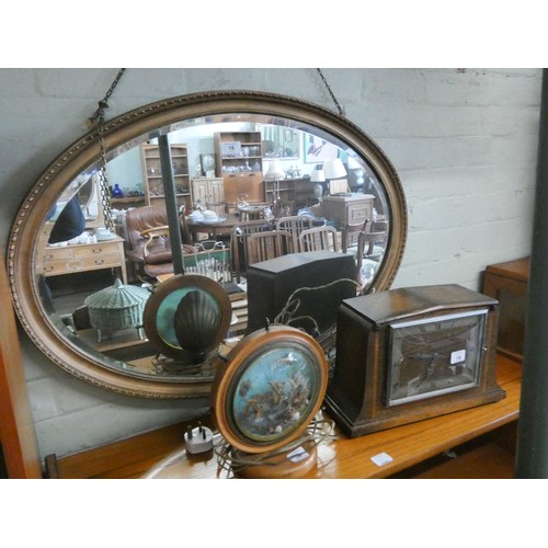 16 - An oval bevelled wall mirror in a gilt frame, a mantle clock and a vintage fish aquarium style table... 