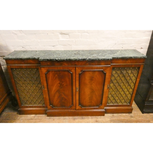 12 - A Regency style mahogany break front sideboard with two panel and two grill doors, with green patter...