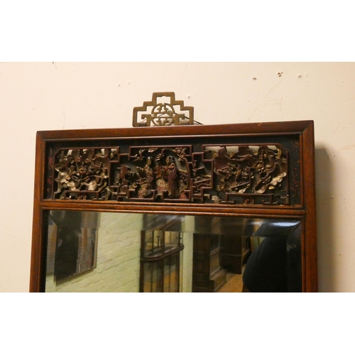 22 - A Chinese mahogany bevelled wall mirror with carved panel to the top and bottom, overall size 38