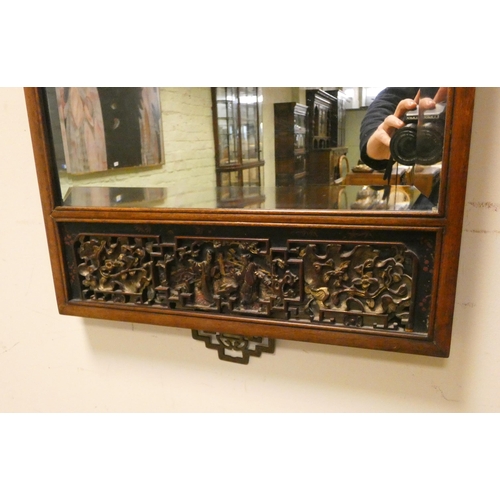 22 - A Chinese mahogany bevelled wall mirror with carved panel to the top and bottom, overall size 38