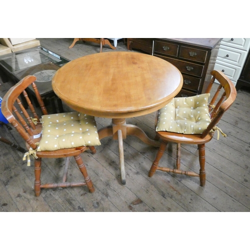 88 - A circular pine finished breakfast table on tripod base and a pair of pine Windsor style chairs