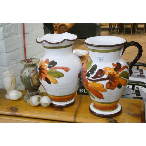 162 - A large floral decorated jug with matching vase, two onyx vases and three eggs