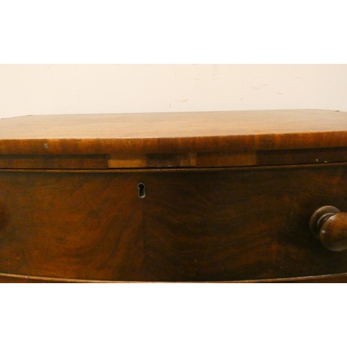 85 - A Victorian mahogany bowfront chest of three long drawers with bun handles standing on turned feet, ... 