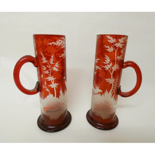 241 - A pair of Bohemian ruby glass etched flagons decorated with deer stags in a forest, each measuring 9... 