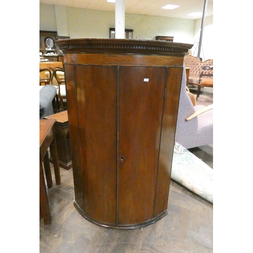 334 - A Georgian convex mahogany hanging corner cabinet with key