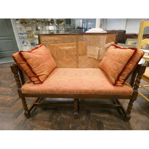 341 - A 1920's mahogany framed Bergere two seater sofa with barley twist front columns and fringed paisley... 