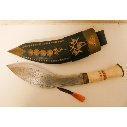 244 - A Kukri in a brass studded and coin decorated leather scabbard